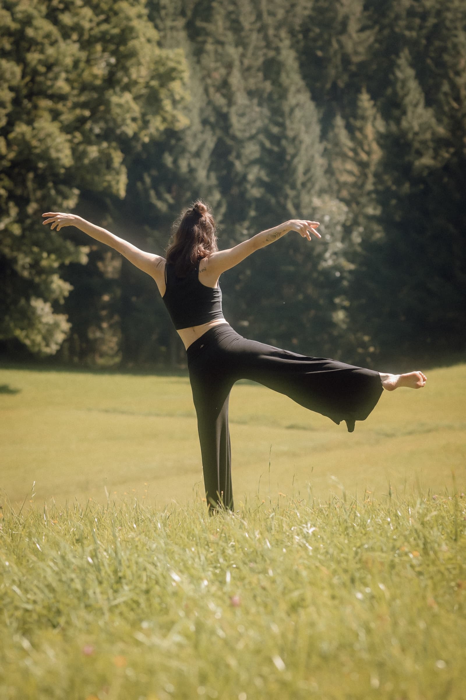 Lisa in einer Yoga-Pose in einer Sommerwiese